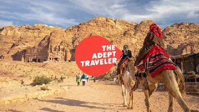 A traveler riding a camel through the desert of Jordan to experience the ruins of Petra