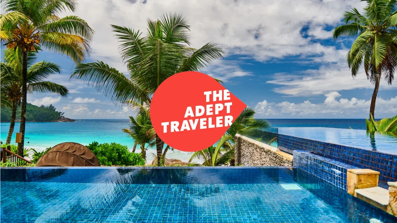 View of a pool, palm trees, and a beach from a high end all inclusive resort.