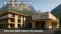 Aman Rosa Alpina's minimalist stone-and-glass exterior sits beneath soaring Dolomite peaks on a clear summer day.