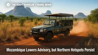 Safari truck navigates dusty Niassa Reserve track amid granite hills under bright sky, illustrating Mozambique travel advisory.