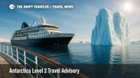 Expedition ship beside towering iceberg under crisp Antarctic sun, visualizing the Level 2 Antarctica travel advisory.