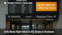 Departures board at Newark shows delays during FAA staffing shortage, warning signage advises travelers to check flight status and expect longer waits