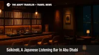 Warmly lit Saikindō bar at Four Seasons Hotel Abu Dhabi with vinyl shelves, wood and brass counter, and guests enjoying Japanese inspired cocktails