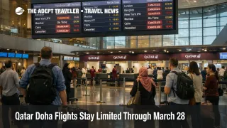 Travelers wait under departure boards at Doha as Qatar Doha flights remain limited through March 28, 2026