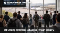 Passengers wait near an arrivals board at SFO as landing restrictions raise San Francisco airport delay risk